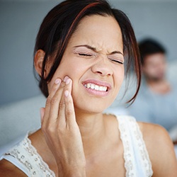 Grimacing woman holding jaw in pain