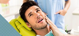 Man in dental chair holding cheek